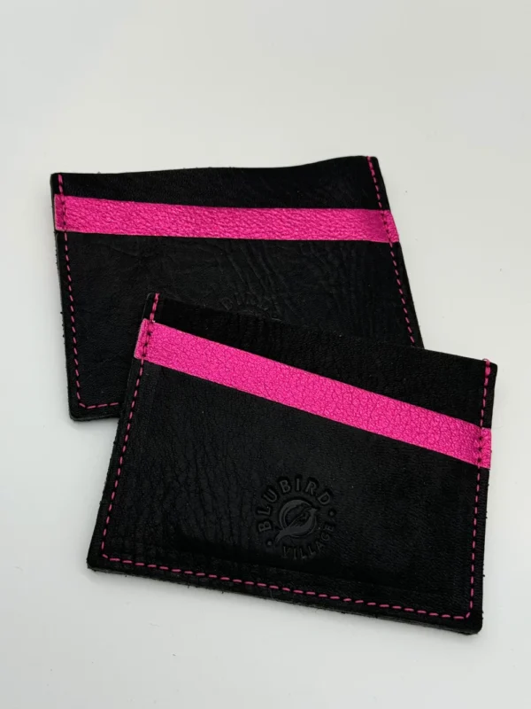 A pair of black and pink wallets sitting on top of a table.