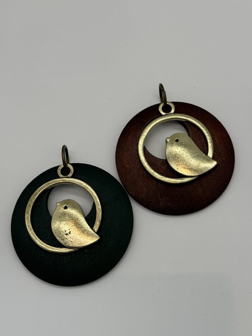 A pair of bird earrings sitting next to each other.