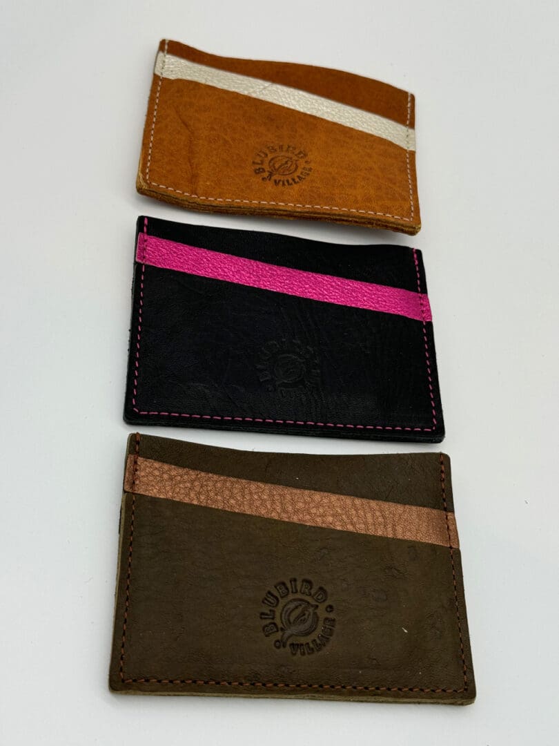 Three different colored wallets are shown on a table.