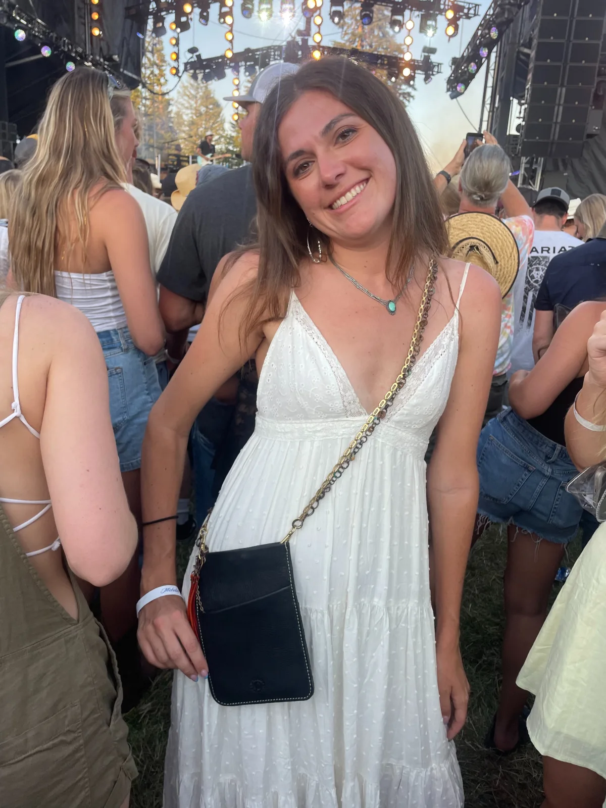 A woman in white dress holding onto a black purse.