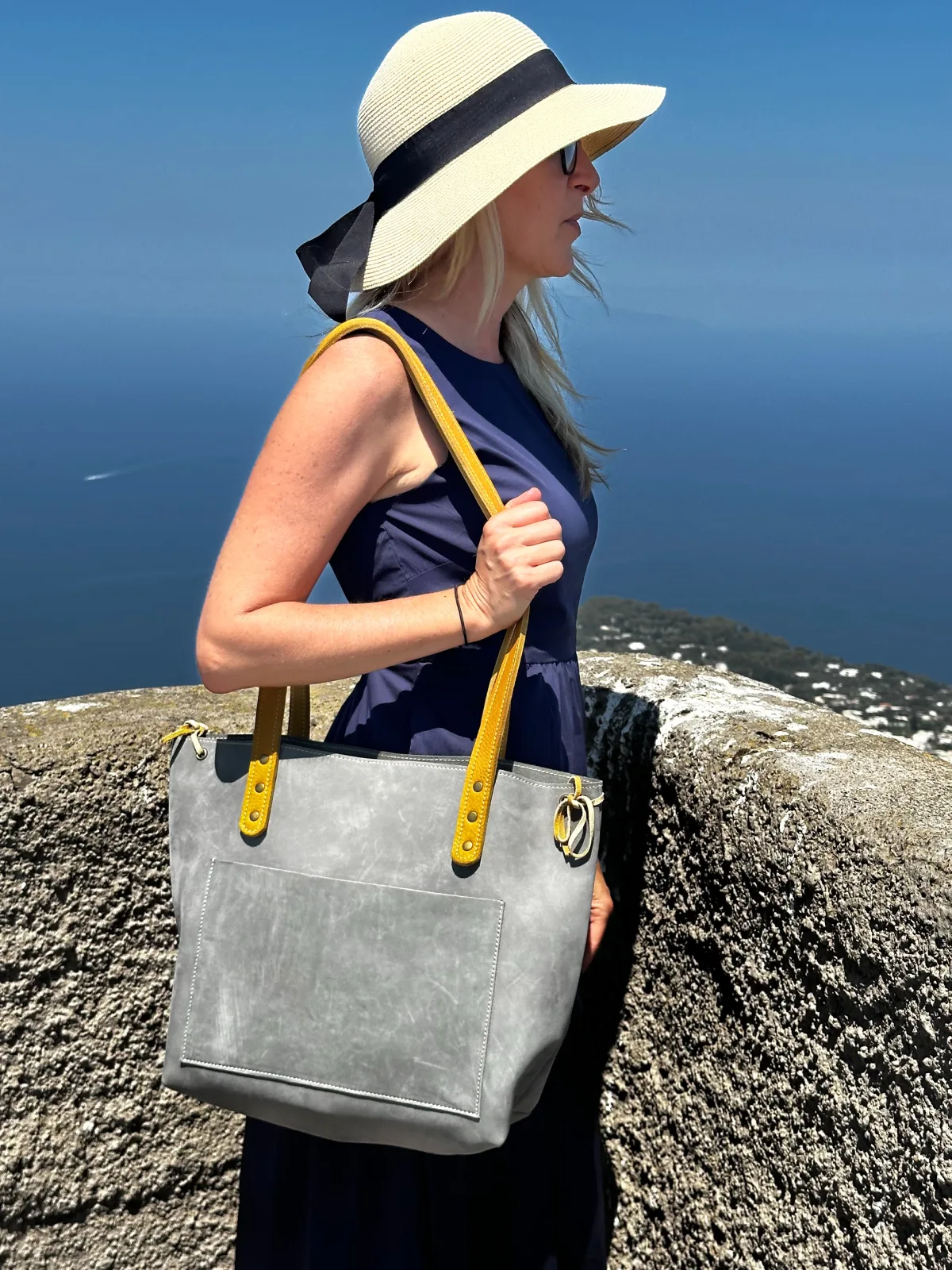 A woman standing on top of a hill with a bag.