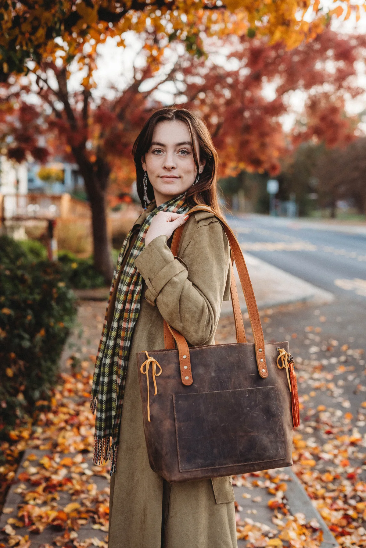 A woman standing on the side of a road holding onto a purse.